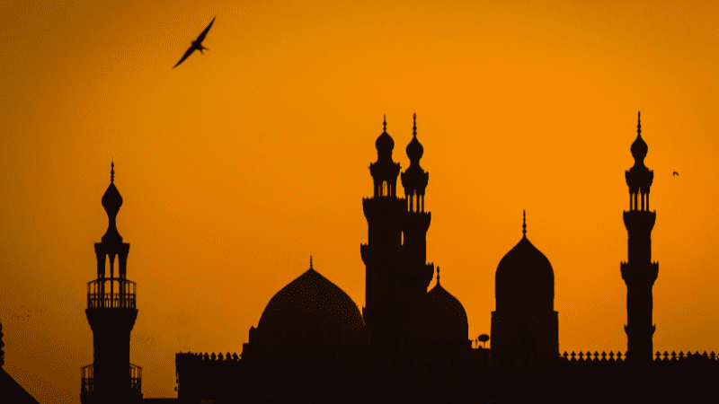 Silhouettes of Islamic minarets and domes against a sunset sky in Cairo.