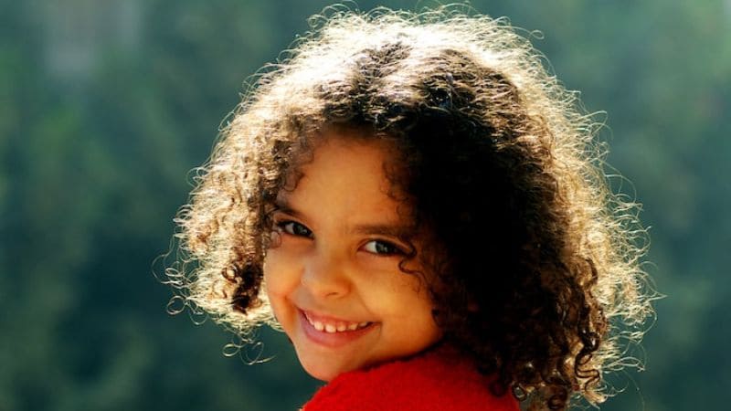 Smiling child with curly hair.