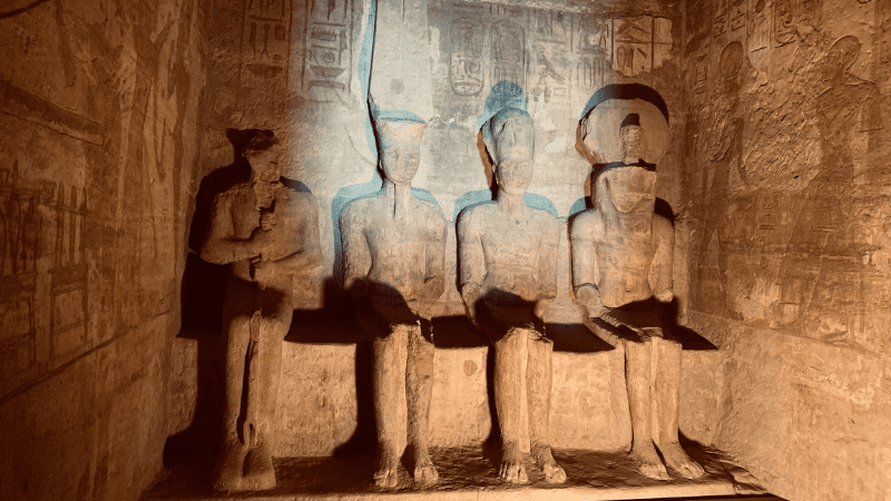 Interior of an Egyptian temple with sunlight on statues
