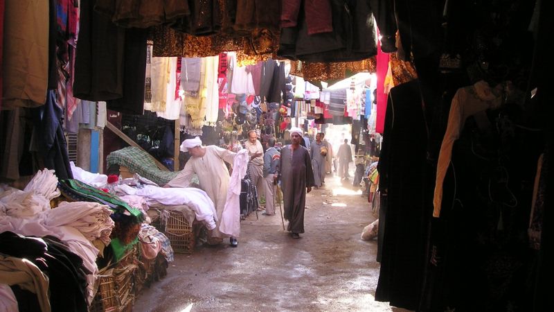 "Bustling alleyway in an Egyptian market with locals and goods."