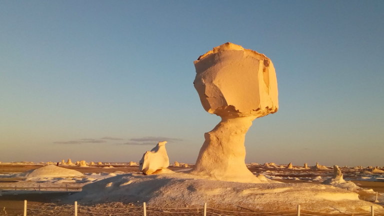 A rock formation resembling a mushroom in the White Desert of Egypt at sunset.