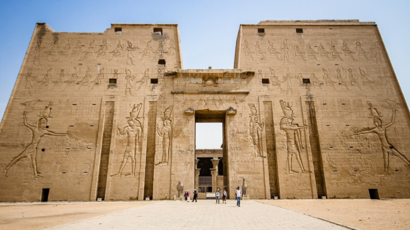 Wide view of the Edfu temple entrance with visitors at the gate