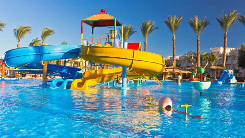 Waterpark with slides and pools surrounded by palm trees.