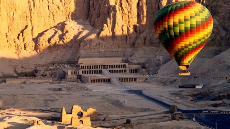 Hot air balloon soaring over the Temple of Queen Hatshepsut in Luxor, Egypt.