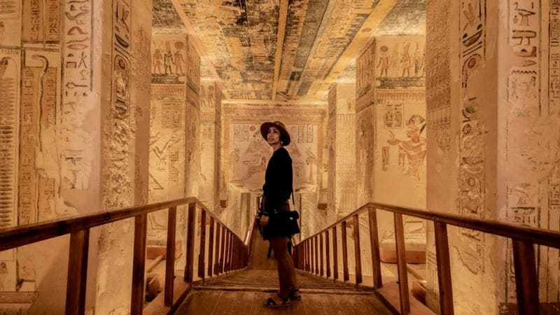 Visitor inside an ornate Egyptian tomb.