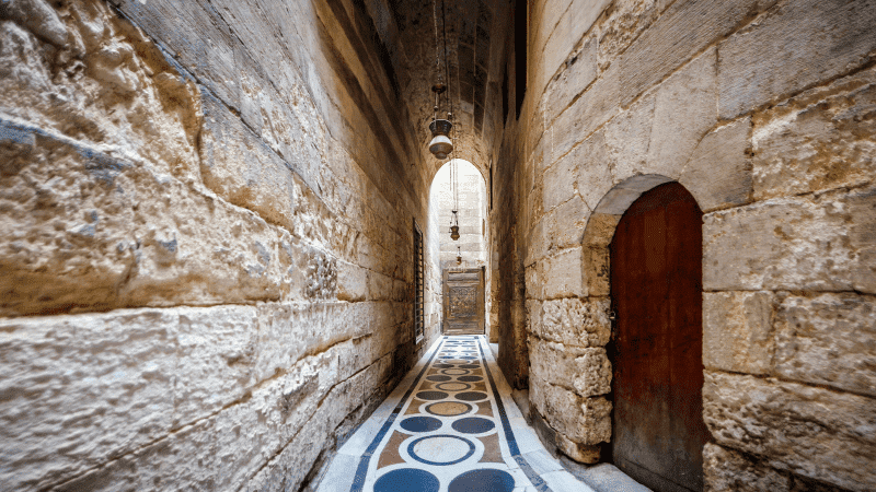 A narrow passage with stone walls and a patterned floor in a historic building