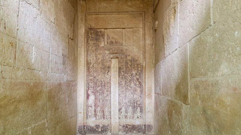 "Faded hieroglyphs inside a narrow chamber of an Egyptian tomb."