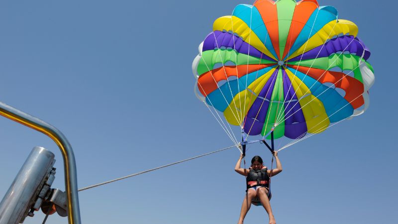 Person parasailing with a colorful parachute over the sea.