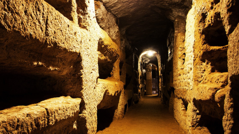 An underground crypt lined with niches carved into the stone walls