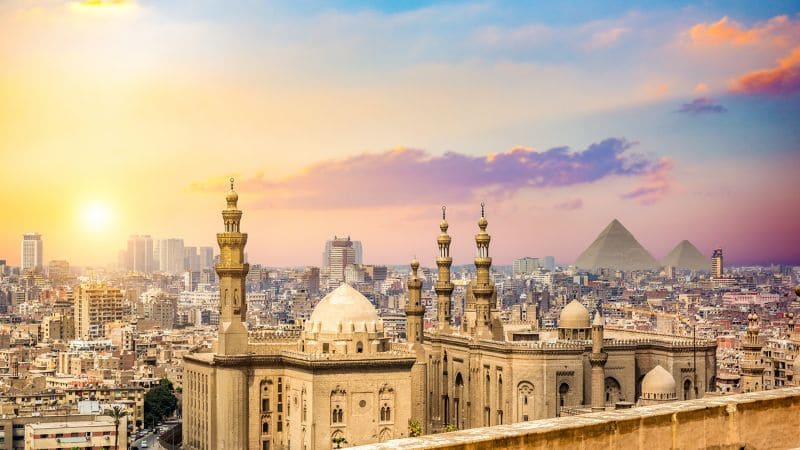 Cairo skyline with mosques and pyramids.