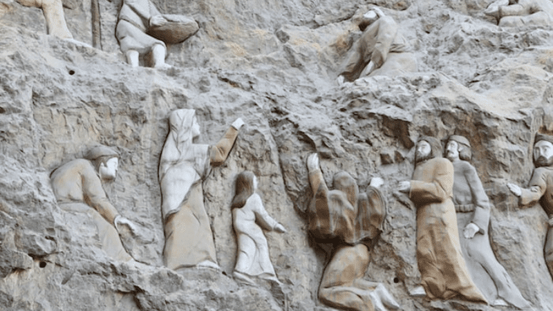 Carved figures ascending a rocky cliff.