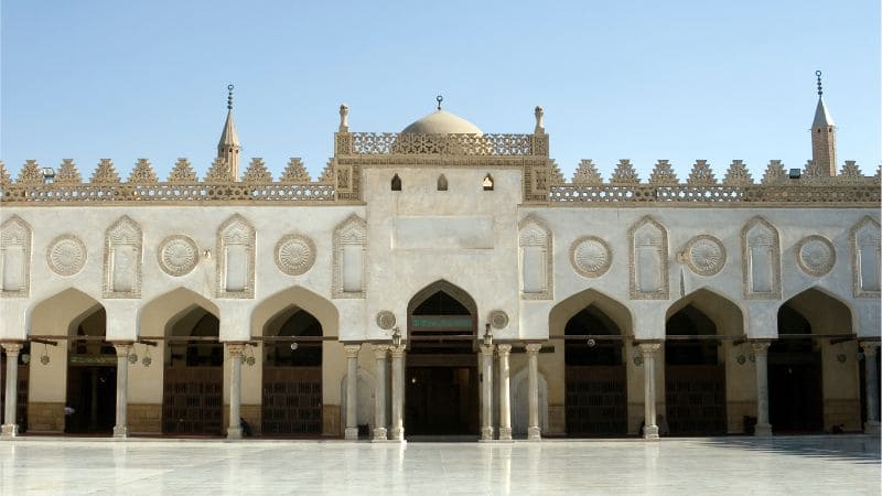 Front view of a mosque with arched doorways and a dome.