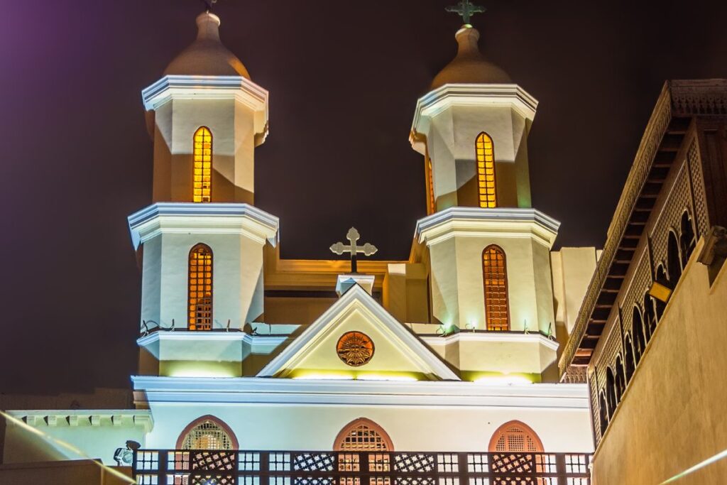 Illuminated twin bell towers of a Coptic church at night.