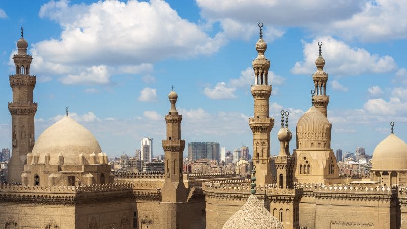 A panoramic view of Cairo's skyline dominated by intricate mosque minarets and domes.