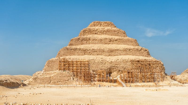 The Step Pyramid of Djoser surrounded by desert, with scaffolding indicating restoration.