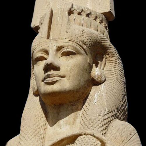 A close-up of an ancient Egyptian statue's face with a headdress and cobra symbol