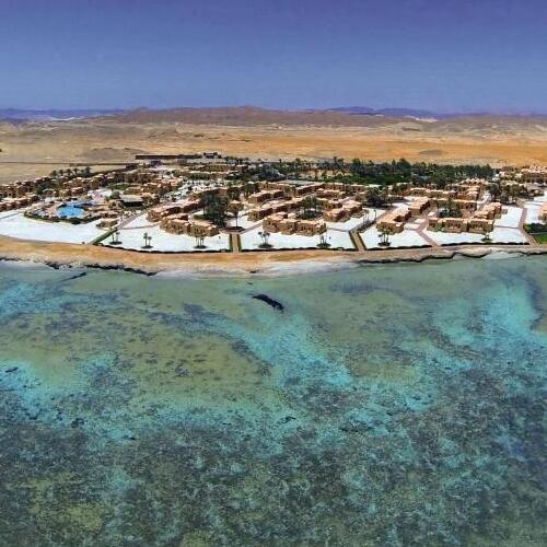 Aerial view of a coastal resort town with clear blue waters adjacent to an arid desert