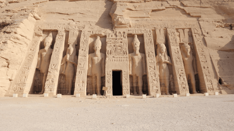 Ancient Egyptian temple exterior with colossal statues at the entrance.