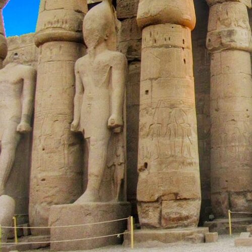 Ancient sandstone statues towering among the pillars of Luxor Temple in Egypt