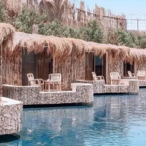 Thatched roof cabanas by a serene blue swimming pool