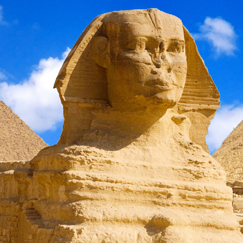 Image of the Great Sphinx of Giza with the Pyramids in the background under a clear blue sky