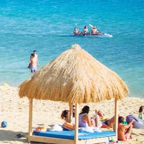 People relaxing on the beach and paddling on the sea at a sunny beach resort