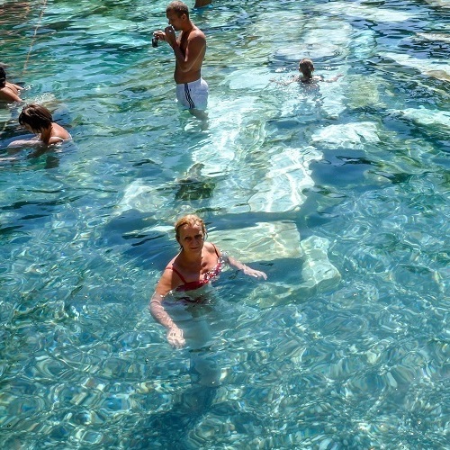 People enjoying a swim in the clear, turquoise waters of a natural pool
