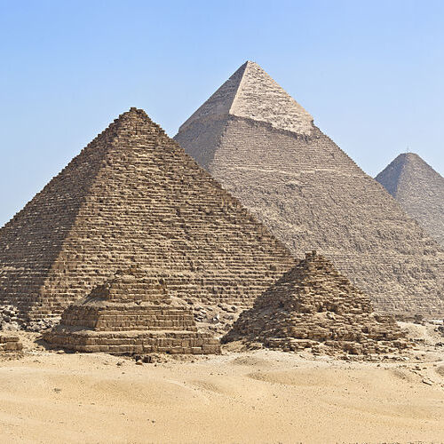 Three ancient pyramids standing against a clear blue sky in the Giza Necropolis.
