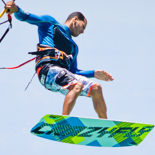 A kite surfer suspended mid-air above the water, performing a trick.