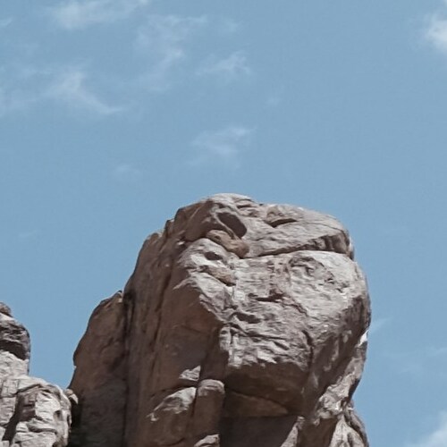 A close-up image of a towering rock formation against a clear blue sky