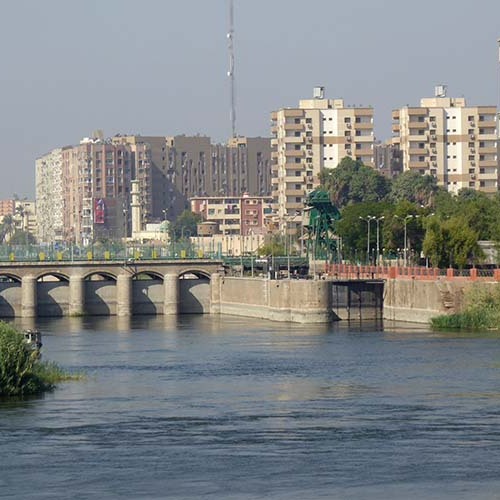 View of a bridge over the Nile River with residential buildings in the background in Asyut, Egypt.
