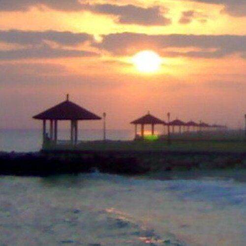 A picturesque sunset over the sea with silhouettes of gazebos on a pier.