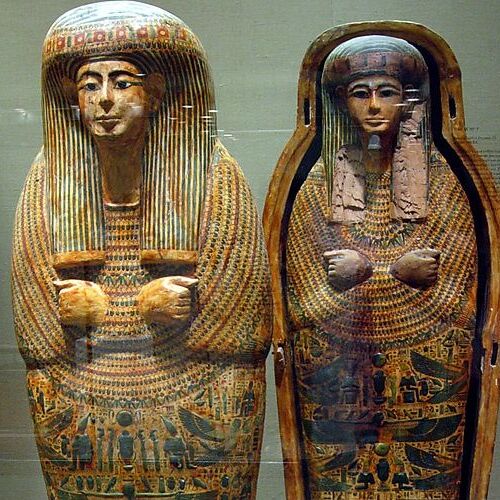 Image of two intricately decorated ancient Egyptian coffins, one closed and one with the lid propped open, displaying hieroglyphs and traditional burial art.