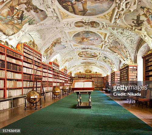 Historic library with ornate ceiling frescoes, wooden bookshelves, and globes.