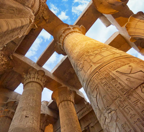Low-angle view of ancient Egyptian hieroglyphs carved on towering columns at the Karnak Temple
