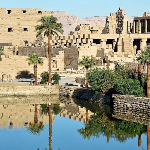 The Sacred Lake in the Karnak Temple Complex, Luxor, Egypt, reflecting the surrounding ruins and palm trees
