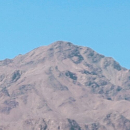 Close-up image of a rugged mountain summit under a clear blue sky