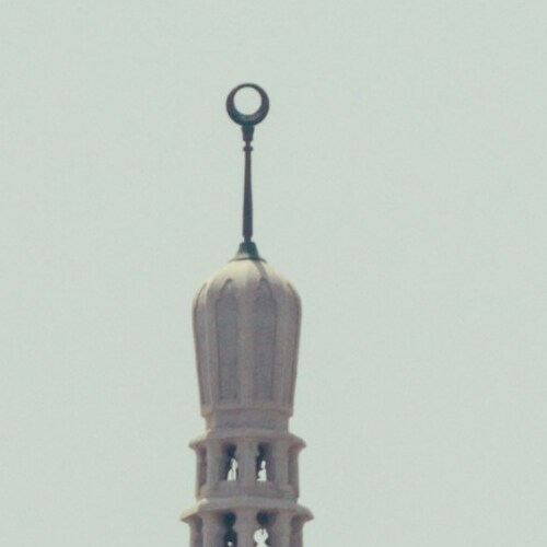 A close-up view of a crescent-topped minaret against the sky