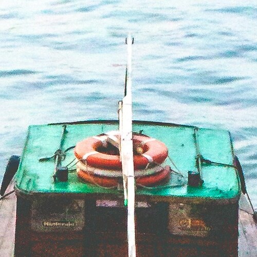 A lifebuoy attached to the stern of a boat on serene water.