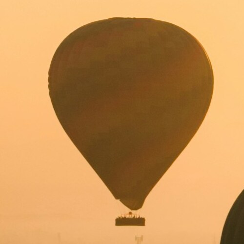 Silhouette of a hot air balloon against a golden sunset sky