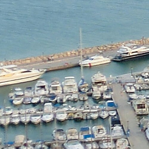 Aerial view of a yacht marina with various sized boats docked in clear waters