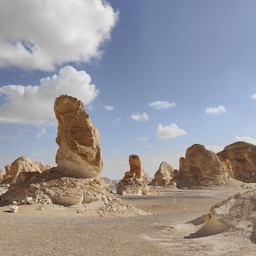 Massive limestone formations standing tall amidst the desert landscape under a clear blue skyThe photograph captures a series of towering limestone formations, sculpted by natural erosion processes, rising from the desert floor, signifying the resilience and enduring beauty of nature."