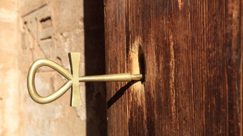 A traditional Egyptian ankh key inserted into a wooden door.