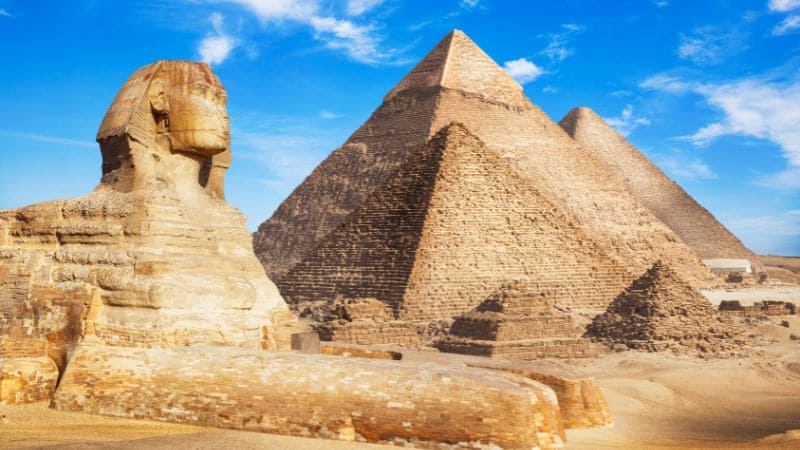 The Sphinx and Pyramids of Giza under a blue sky