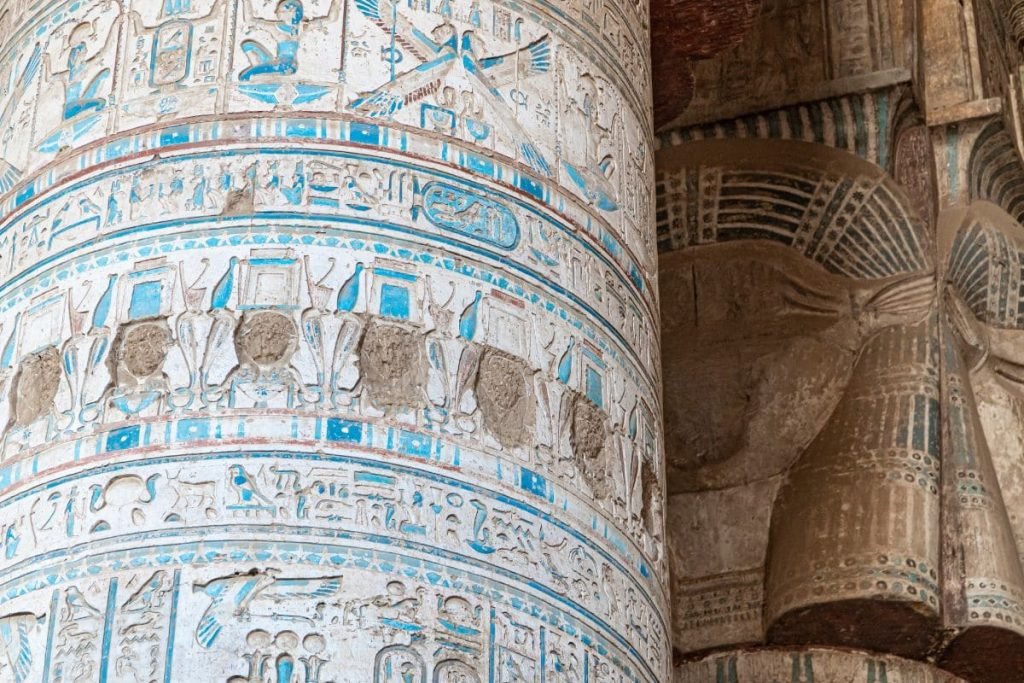 Intricately carved hieroglyphs and figures in vibrant colors inside an Egyptian temple.