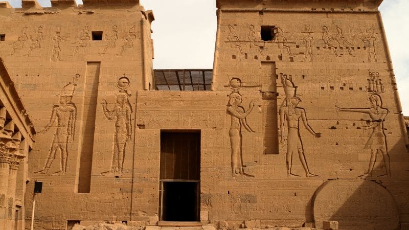 The sunlit facade of the Temple of Philae with carved figures in Egypt.
