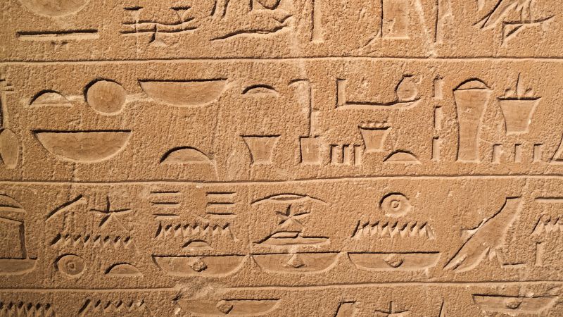 Close-up of ancient Egyptian hieroglyphs engraved in stone.