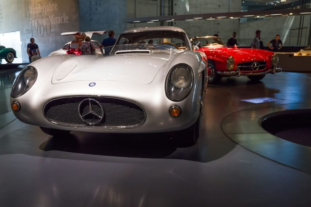 Vintage Mercedes sports car in silver displayed at a car museum with other classic cars in the background