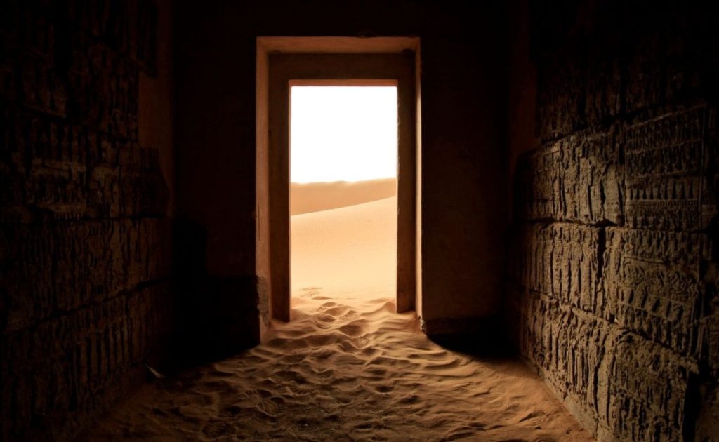 View through an ancient doorway revealing a sunlit desert landscape
