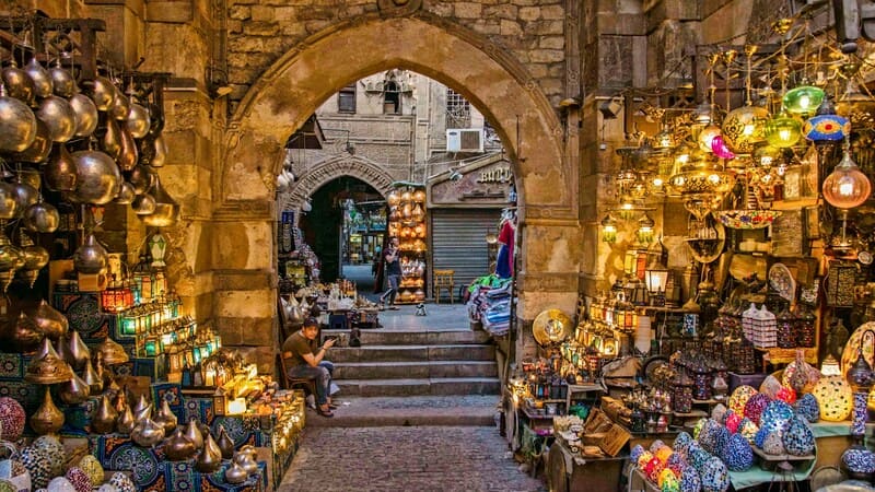 A vibrant marketplace in an old stone archway, adorned with colorful lamps and traditional crafts, capturing the essence of local culture